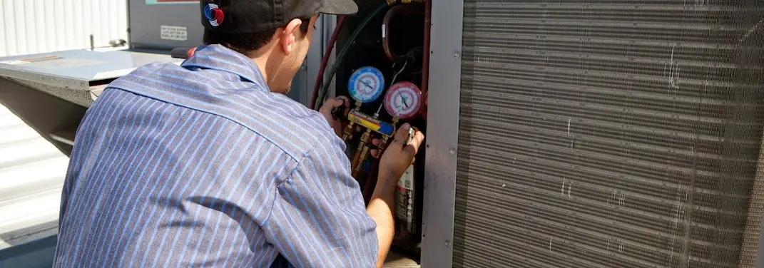 HVAC technician servicing a condenser unit in Hallsville